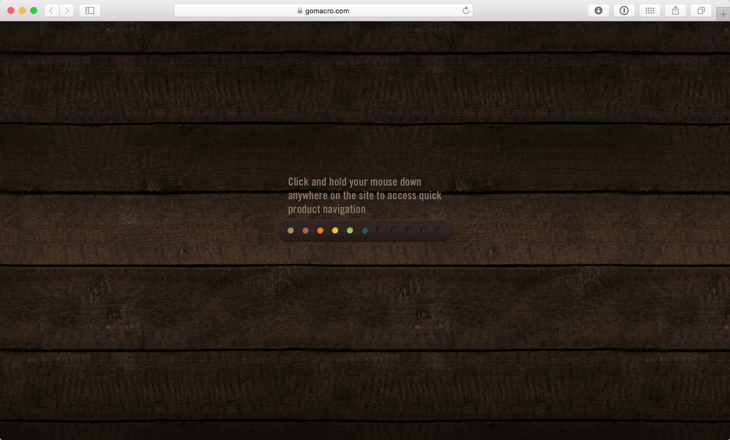 A rainbow loading bar appears over a wooden floor background. Text above the bar reads Click and hold your mouse down anywhere on the site to access quick product navigation.